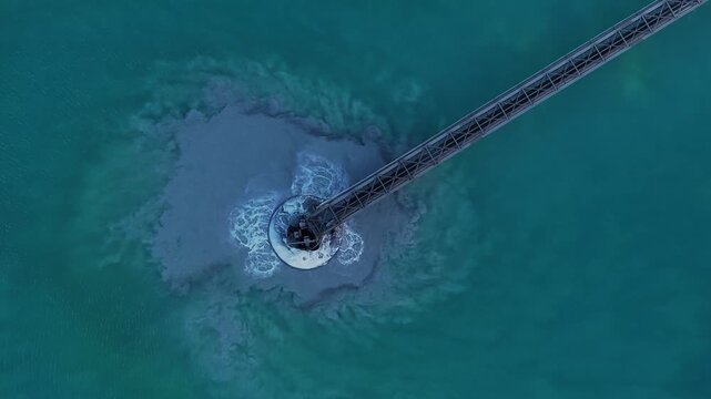 Aerial view of a metal structure in turquoise water, surrounded by a plume of sediment contrasting with the clear water, Arizona, United States.