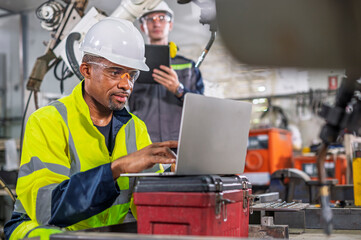 Robotics control engineers setting and maintain spare parts of industrial robot arm controller in production plant factory