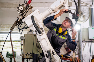 Robotics control engineers setting and maintain spare parts of industrial robot arm controller in production plant factory