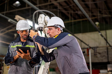 Robotics control engineers setting and maintain spare parts of industrial robot arm controller in production plant factory