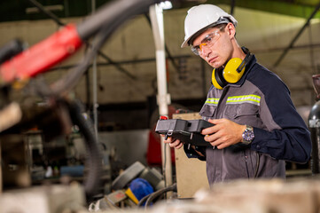Robotics control engineers setting and maintain spare parts of industrial robot arm controller in production plant factory