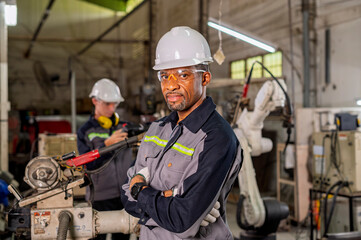 Robotics control engineers setting and maintain spare parts of industrial robot arm controller in production plant factory