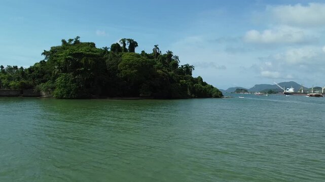 Drone footage from low altitude with the drone approaching the Island Ilha do Coqueiro in Angra dos Reis. The rainforest covered mountains, as well as part of the harbour is in the background