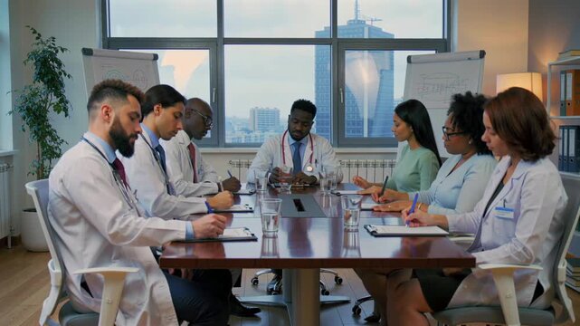 Multicultural medical staff analyzing patient data, Urban hospital team collaboratively reviewing clinical cases, Multiracial healthcare professionals discussing patient charts in conference room