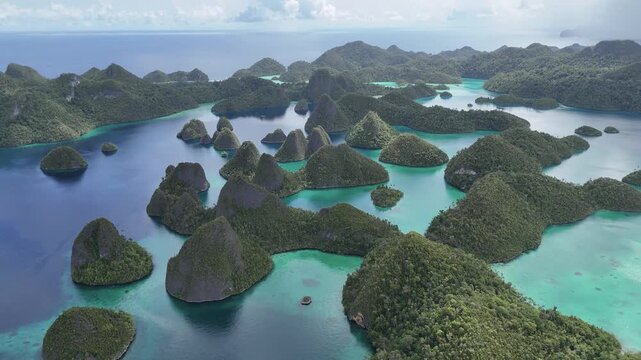 Cinematic aerial drone footage pulling backward over the iconic karst islands of Wayag, Raja Ampat, Indonesia. Dramatic limestone formations rise from turquoise lagoons and deep blue ocean, partially 