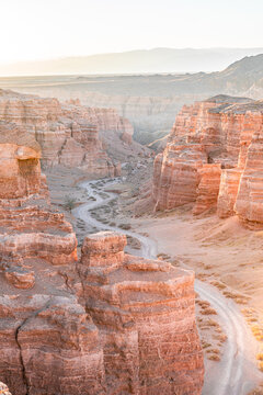 Winding road crossing Charyn Canyon in Kazakhstan, illuminated by the warm light of the sunrise sun Charyn Canyon, Valley of Castles. The excellence of Kazakhstan. Panorama of natural unusual landscap