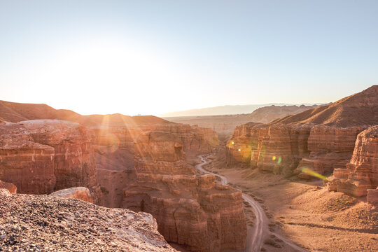 Winding road crossing Charyn Canyon in Kazakhstan, illuminated by the warm light of the sunrise sun Charyn Canyon, Valley of Castles. The excellence of Kazakhstan. Panorama of natural unusual landscap