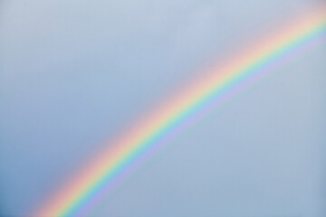 Vibrant rainbow arching across soft blue sky