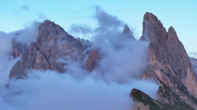 Aerial view of jagged Seceda mountain peaks piercing through a sea of ethereal clouds, showcasing nature's grandeur and drama, Seceda, Trentino-South Tyrol, Italy.