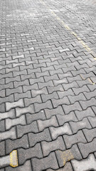 Fototapeta premium Close up view of grey interlocking concrete pavers with yellow parking lines clearly visible.
