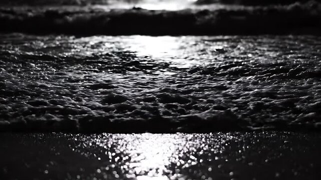Dark, foamy waves crashing on a shore at night, illuminated by moonlight