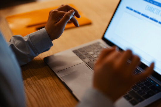 A person's hands are typing on a laptop keyboard, with the screen displaying a character count and writing analysis tool.