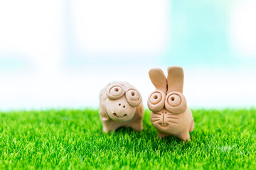 Rabbit and turtle clay sculpture on green grass over blurred background, garden decoration statute