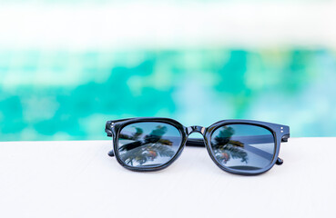 Sunglasses on white wood table with space on blurred water background, outdoor day light