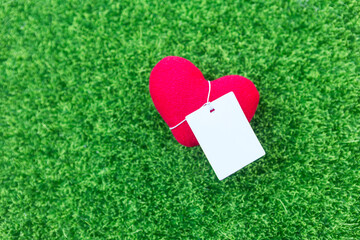 Red heart with price tag on green grass background, valentine background idea