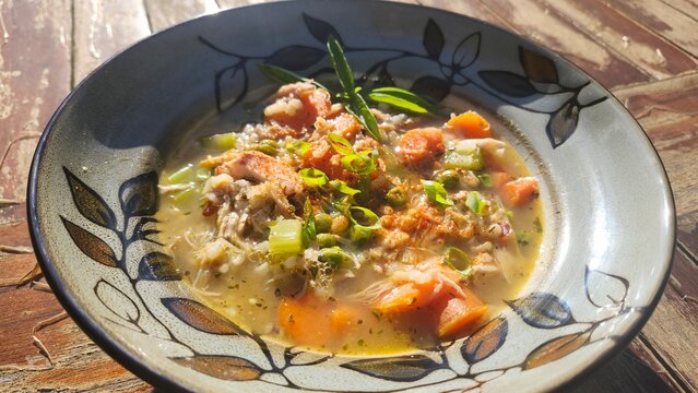 Creamy homemade soup with vegetables and herbs served in decorative bowl