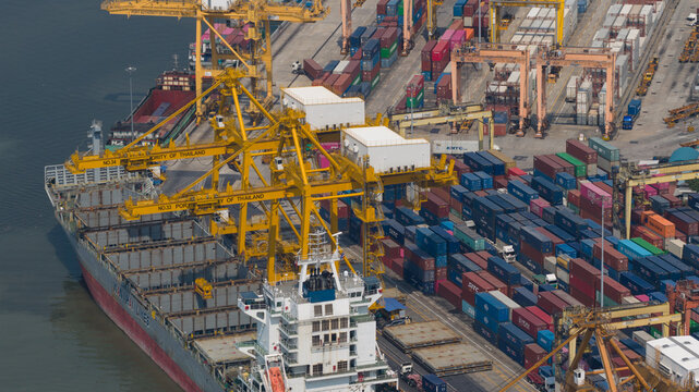 Krung Thep Maha Nakhon, Thailand - 05 February 2026: Aerial view of a cargo ship nestled at Bangkok Container Terminal 2, framed by towering yellow cranes and colorful containers.