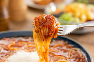 食べる直前のミートソーススープパスタをフォークで持ち上げた瞬間のクローズアップ