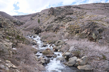 Winter landscape in Caviahue, Neuquen, Argentina: Arroyo de la Usina stream surrounded by rocks and leafless vegetation.