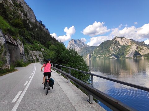 Tourist on a bicycle next to Lake Traun (Traunsee) in Salzburg State, Austria. Woman cyclist on Salzkammergut Cycling Route (Salzkammergut-Radweg).
