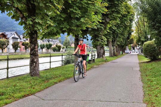 Tourist on a bicycle along River Traun in Bad Ischl, Salzburg State, Austria. Woman cyclist on Salzkammergut Cycling Route (Salzkammergut-Radweg).