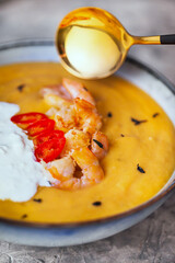 Delicious fresh cooking hot pumpkin and sweet potato soup, served with prawns, chili and stracciatella cheese