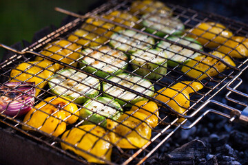 Grilled vegetables (zucchini and bell pepper) on barbecue, green grass background, summer outdoor