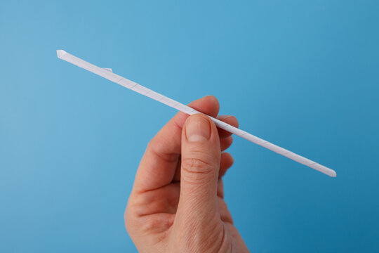 Close up of hands making paper straw or tube using skewer. Concept for eco friendly packaging, sustainable lifestyle, reducing plastic, manual manufacturing, simple diy solution, innovation