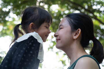 Fototapeta premium Loving mother and young daughter sharing a tender moment outdoors in natural light. Shows emotional bonding, positive parenting, childhood innocence, trust, warmth surrounded by peaceful green nature.