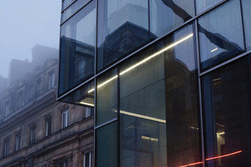 A striking fusion of modern glass architecture framed by an atmospheric fog, showcasing the elegance and complexity of contemporary urban design and structures.