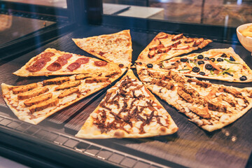 Pizza slices showing variety of toppings in a restaurant food display
