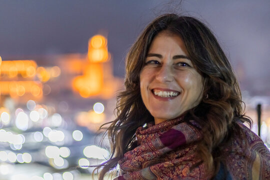 Smiling woman with the iconic and famous Jamaa el Fna square in the background, city lights blurred in the background. Jamaa el Fna,Marrakech,Unesco hertage,Morocco
