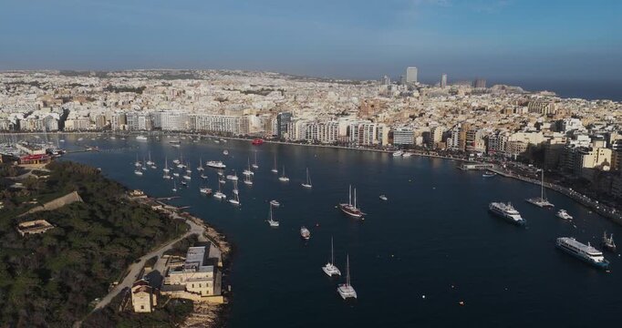 Aerial view of the bustling harbor, with boats dotting the dark blue water against the backdrop of the city skyline, Fort Manoel, Il-Gzira, Malta.
