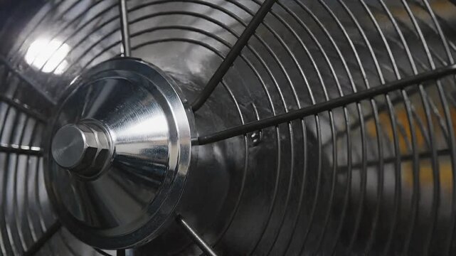 Close-up of a metallic fan with a circular grille design  
