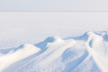 Snow dunes stretch across sunlit winter landscape
