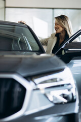 Woman in a car showroom choosing a car