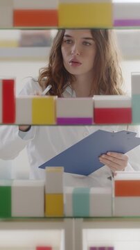 Female Pharmacist Checking Medication Inventory in Pharmacy