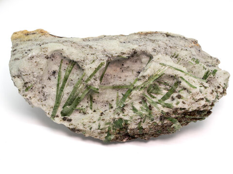 Natural specimen of green actinolite crystals embedded in white host rock, displaying elongated prismatic formations and raw mineral texture