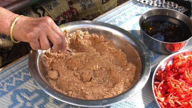 mixing powder masala for making homemade achar by elderly woman.