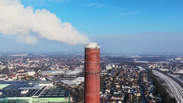 Close up static aerial shot of a smoking chimney of a district heating plant emitting steam over Bielefeld, Germany, during winter