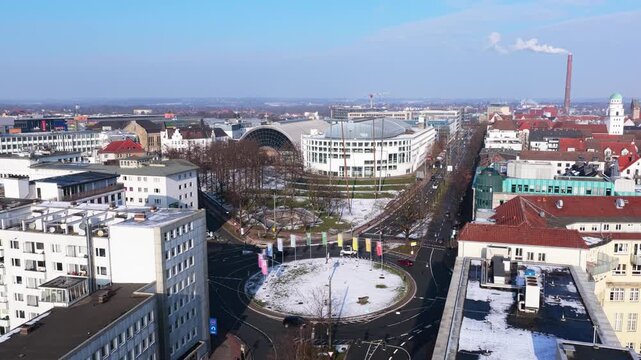 Aerial view flying backwards revealing snowy roundabout of Willy Brandt Platz and urban landscape of Bielefeld, Germany during winter season