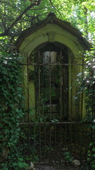 Abandoned stone mausoleum hidden in overgrown forest, rusted iron gate and ivy covered archway bathed in dappled sunlight create haunting and mysterious atmosphere