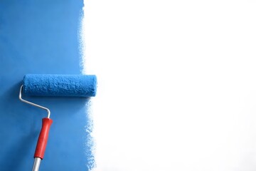Obraz premium A person rolls blue paint onto a wall with a paint roller. The wall shows a clear line between the unpainted and painted sections. The setting is bright and focused on the painting task
