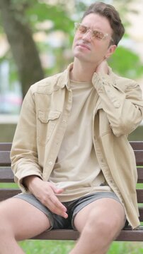 Tired Casual Young Man Sitting Outdoor with Neck Pain, Vertical Video