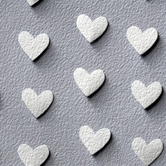 Fototapeta premium White heart shapes scattered on textured gray paper background, creating soft and romantic pattern with handmade feel and subtle shadows for depth