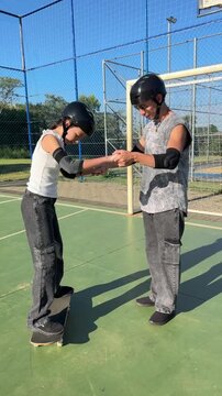 professor e aluna aprendendo equ&iacute;librio com skate ao ar livre 