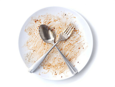 fork and spoon on plate. Empty dirty white pate with crossed spoon and fork after meal isolated on white background
