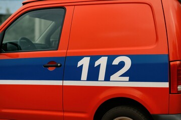 Close-up of an orange emergency van with the number 112 on the side. Represents emergency services, safety, assistance. Use for articles, blogs, websites related to security.