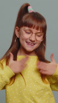I am the best. Happy satisfied selfish haughty toddler girl in glasses proud of her victory bragging own success win achievements, pointing fingers on herself with smile. Child kid on gray background.