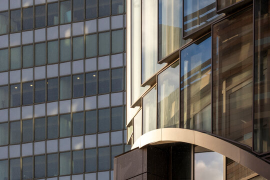 Curved glass facade in modern urban architecture with reflective windows and repeating pattern creating clean abstract background texture